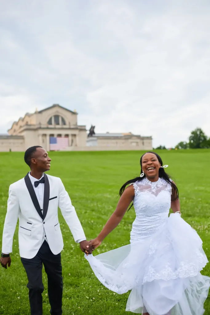 Bride laughing as the couple run hand in hand across a wide green lawn