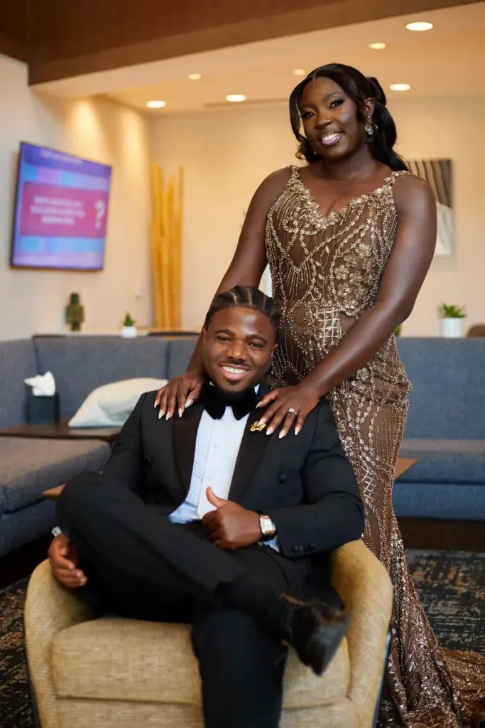 Bride standing behind the seated groom, hands on his shoulders
