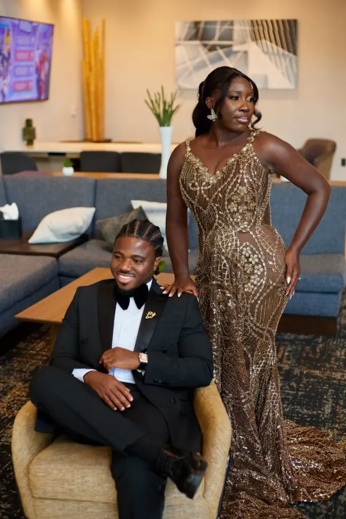 Bride standing in her gown, groom seated beside her