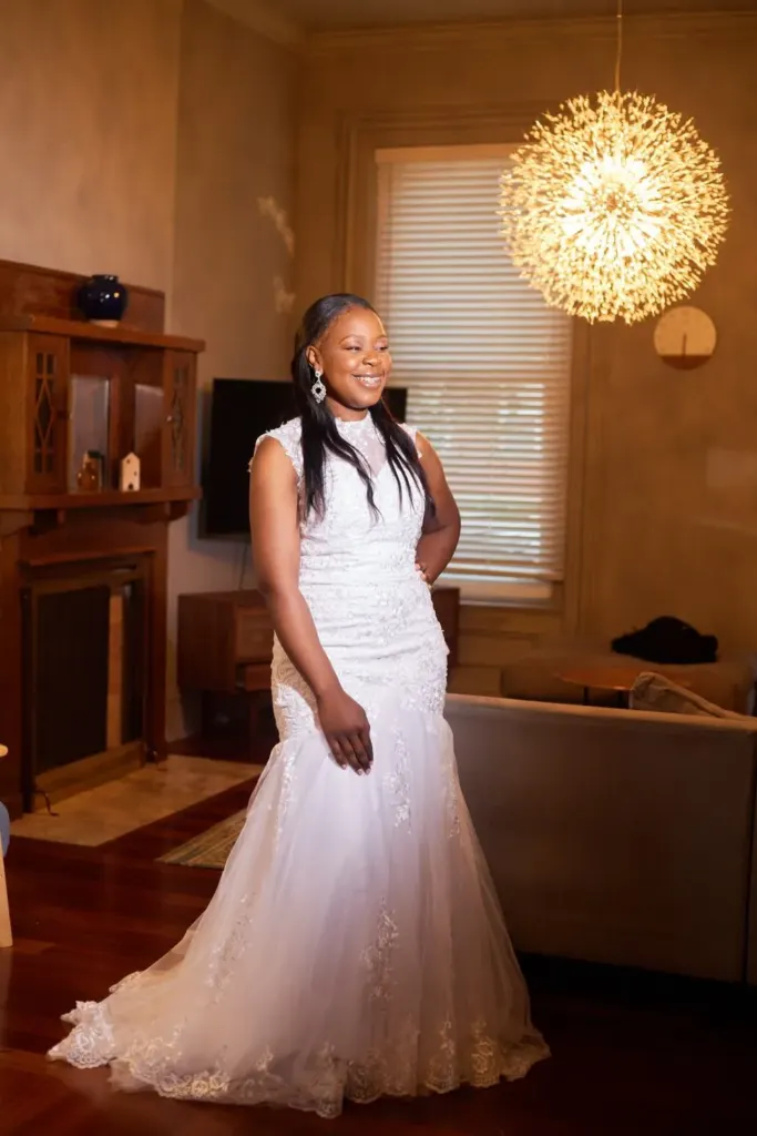 Bride in a lace mermaid gown, smiling in warm window light